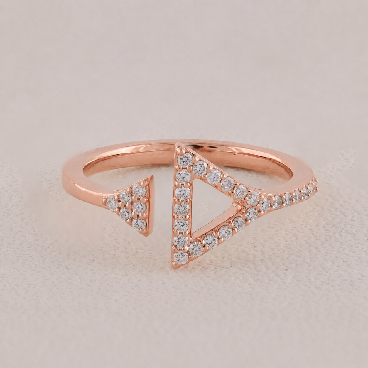Rose gold ring with triangle design and diamonds on a light background