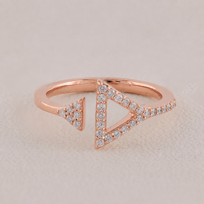 Rose gold ring with triangle design and diamonds on a light background