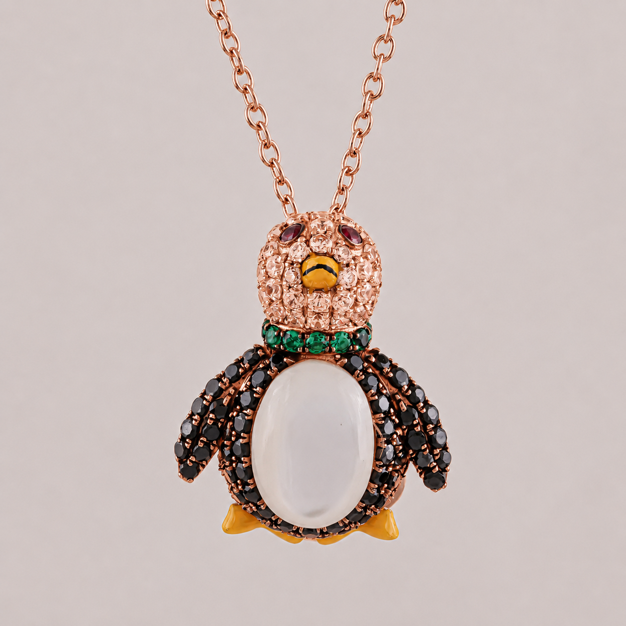 Penguin-shaped necklace with rose gold chain on a light gray background