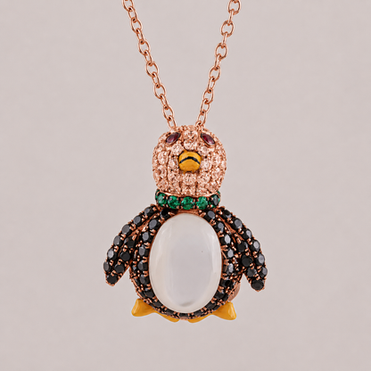 Penguin-shaped necklace with rose gold chain on a light gray background