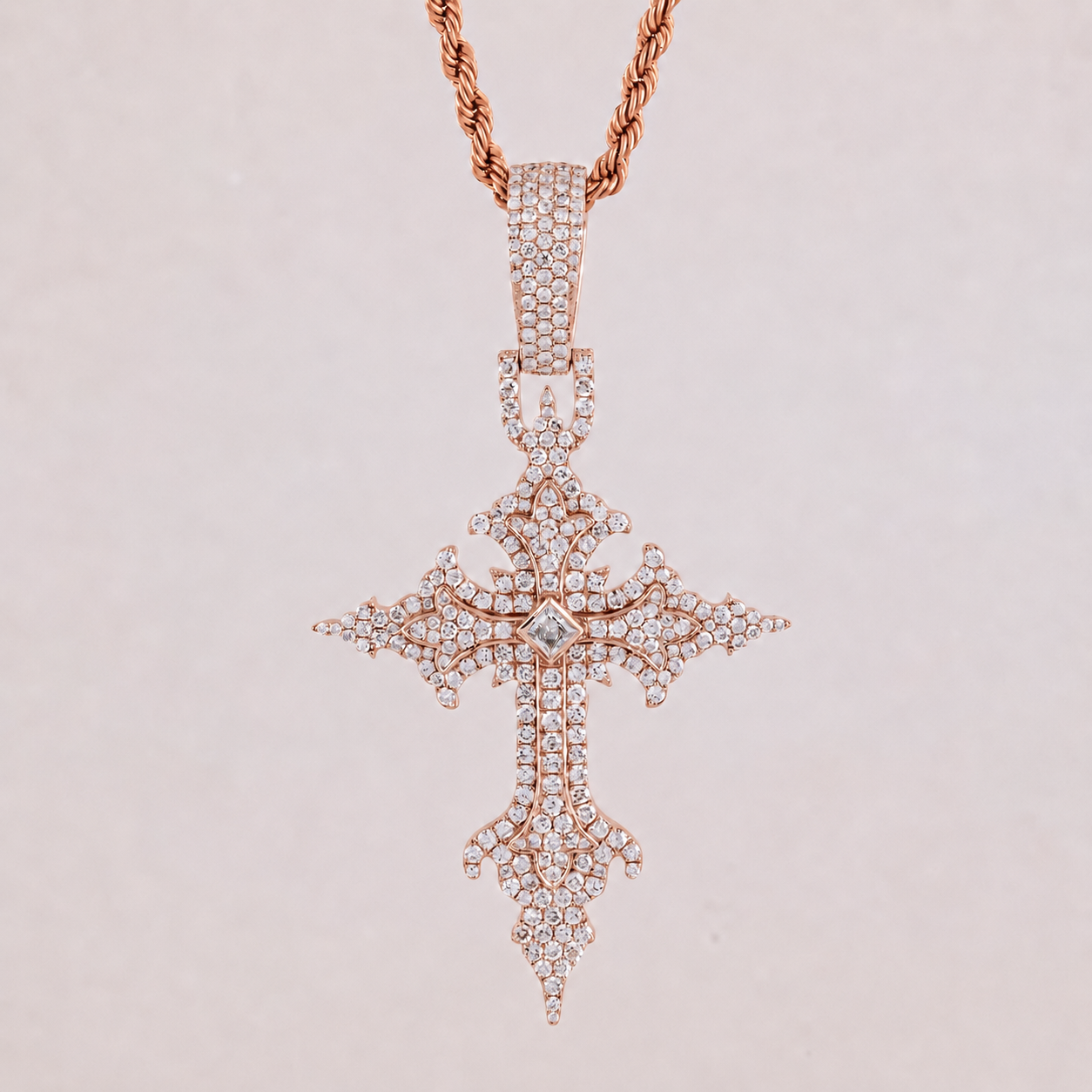 Rose gold cross pendant with diamonds on a light pink background