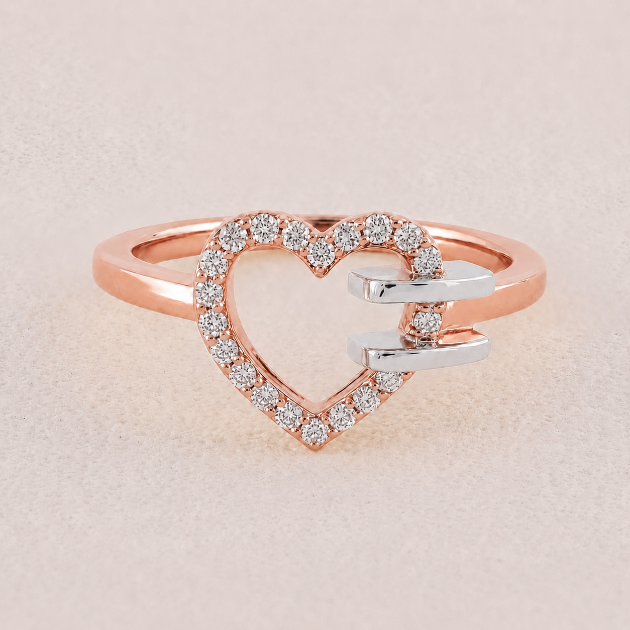 Heart-shaped ring with rose gold and silver tones on a light beige background