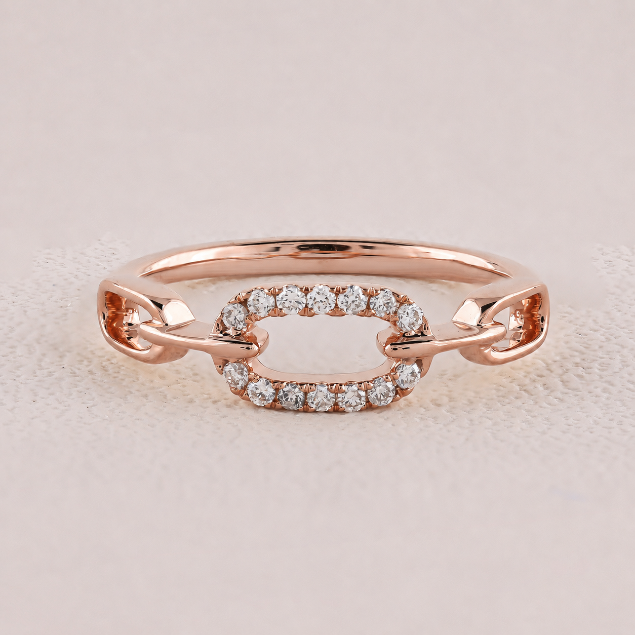 Rose gold ring with diamond accents on a light pink background
