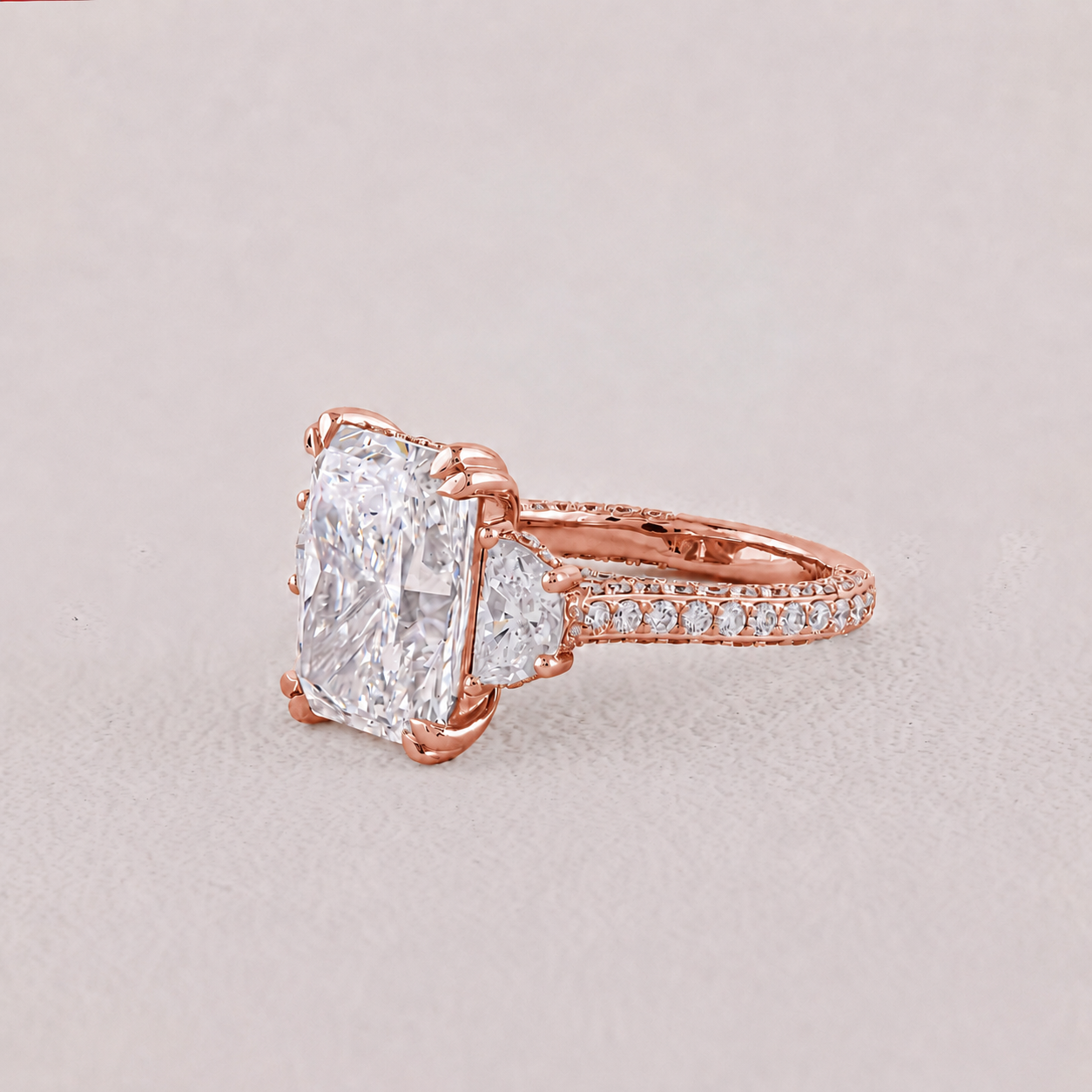 Rose gold ring with a large diamond and smaller diamonds on the band against a light gray background