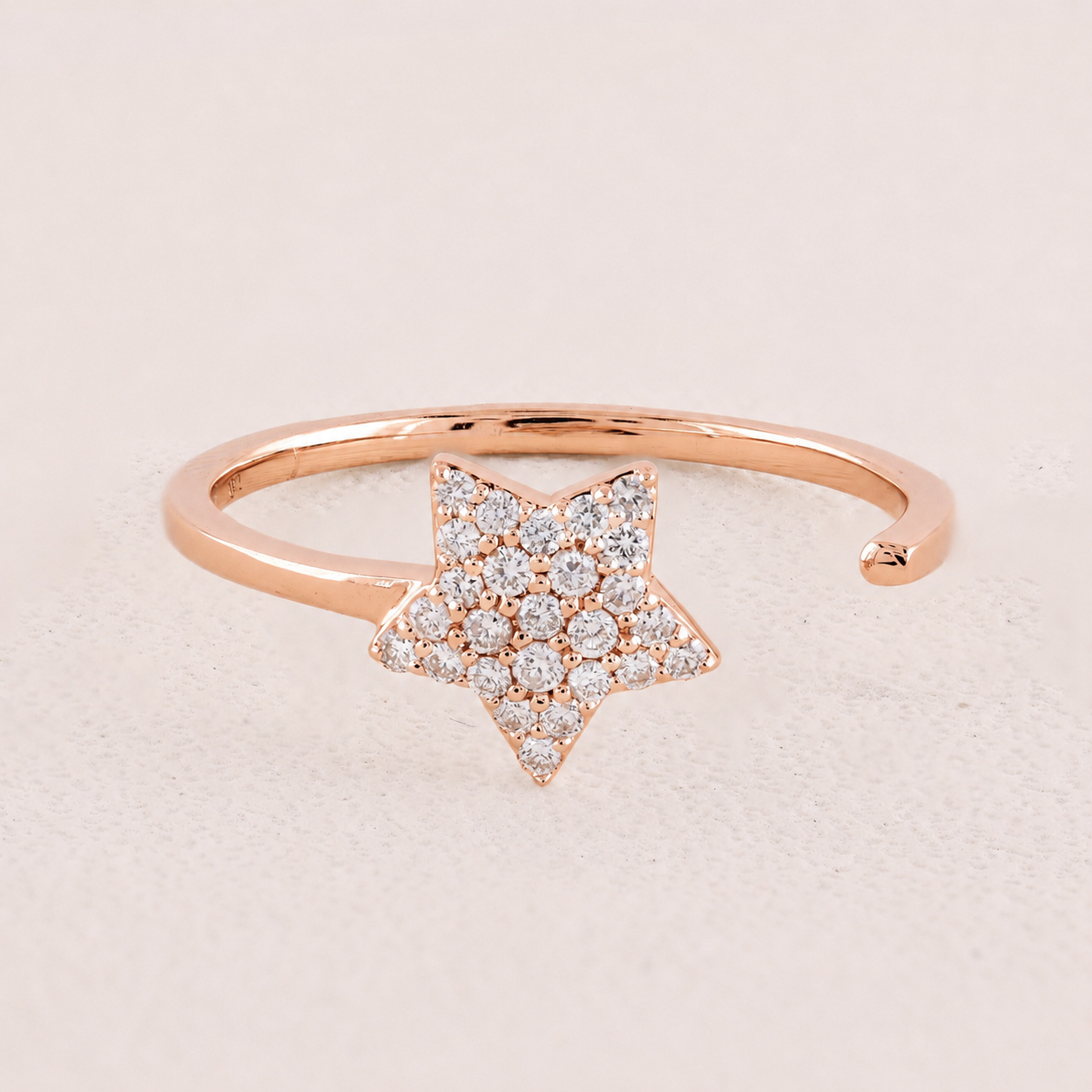 Rose gold bracelet with a star-shaped clasp on a light pink background