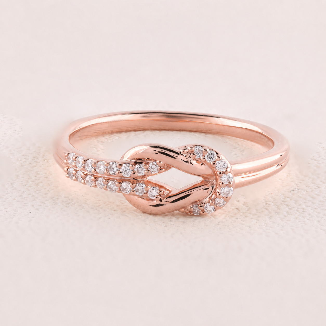 Rose gold ring with diamonds on a light pink background