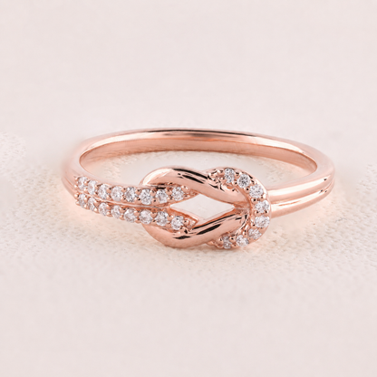 Rose gold ring with diamonds on a light pink background