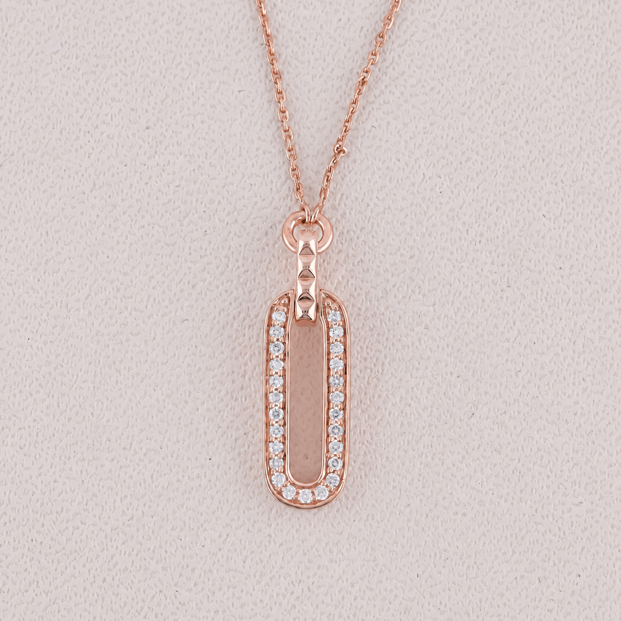 Rose gold necklace with a rectangular pendant on a light gray background