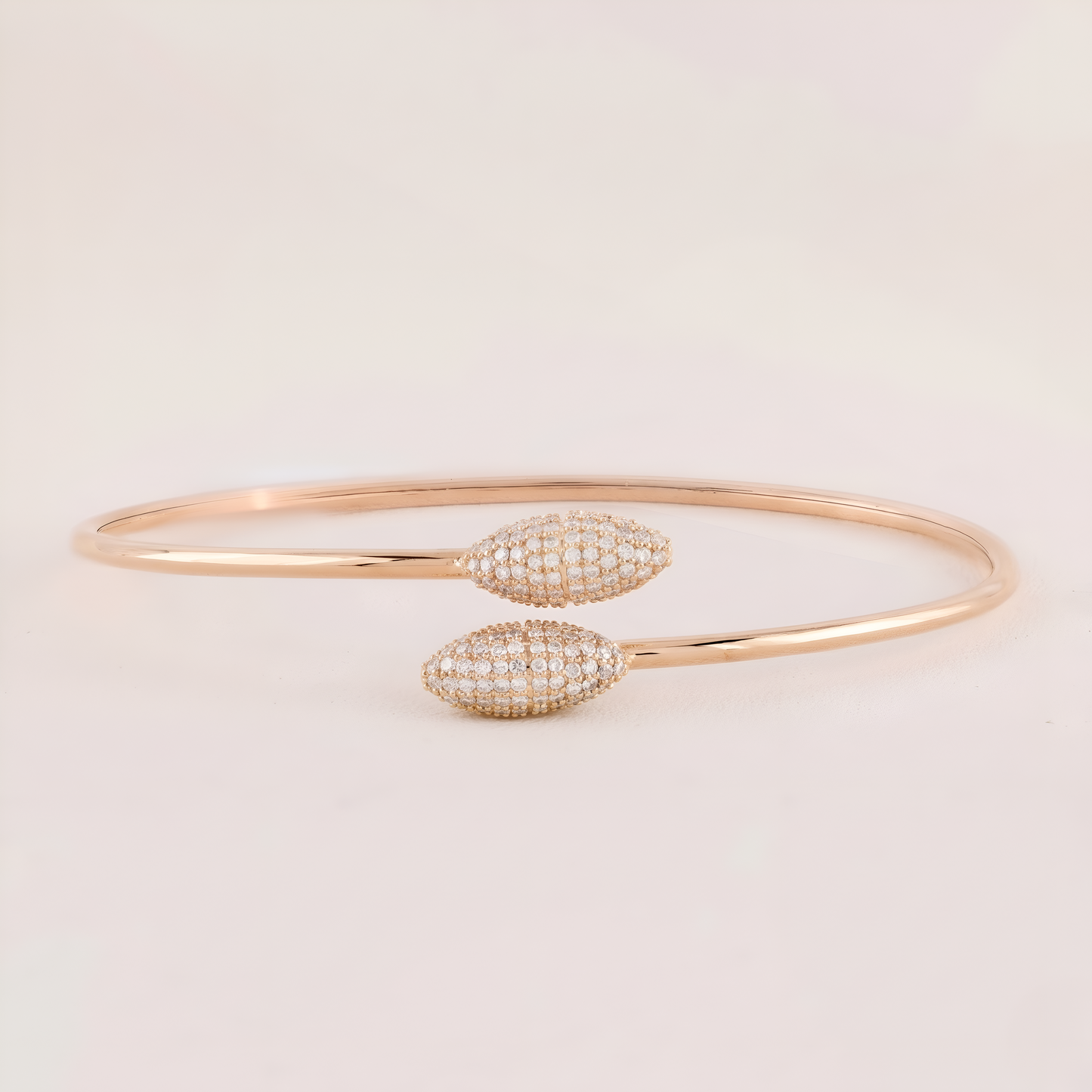 Rose gold bracelet with diamond accents on a light beige background