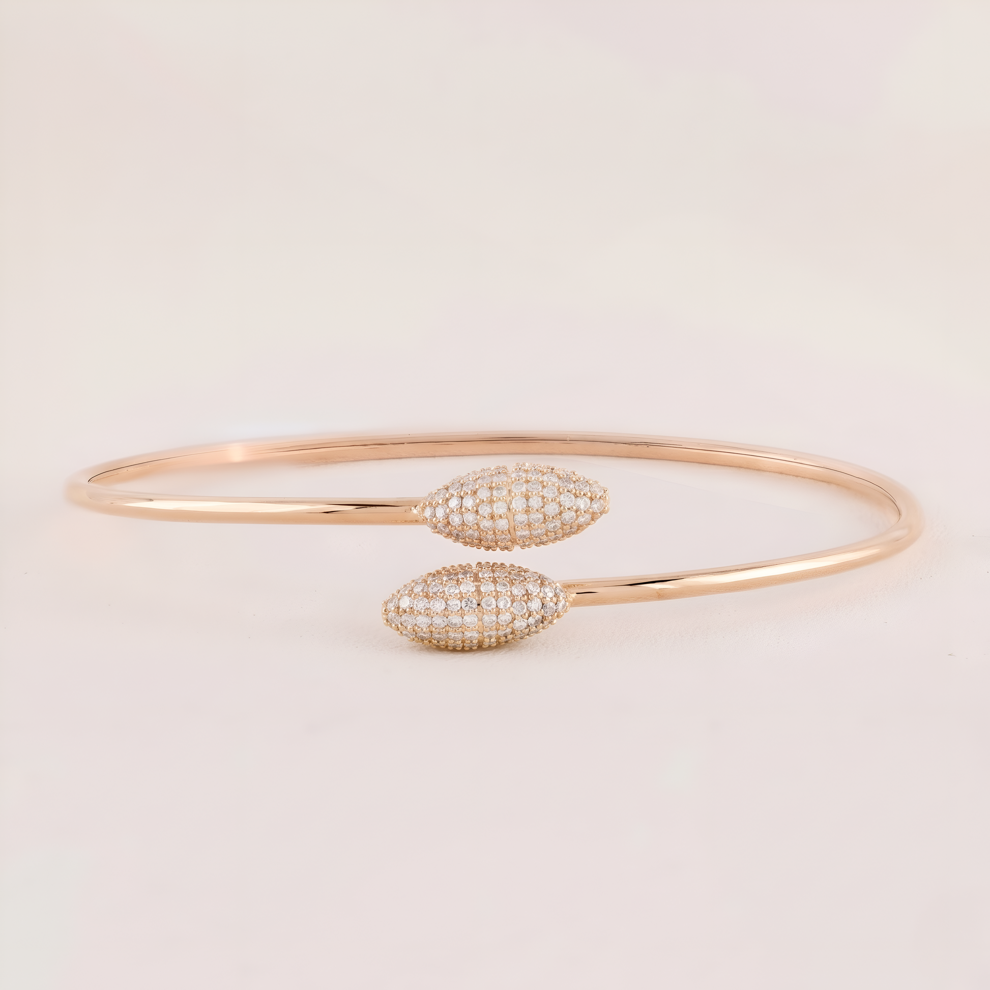 Rose gold bracelet with diamond accents on a light beige background