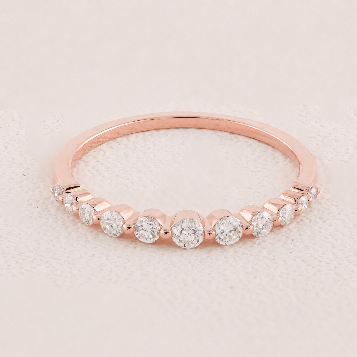 Rose gold ring with diamonds on a light pink background
