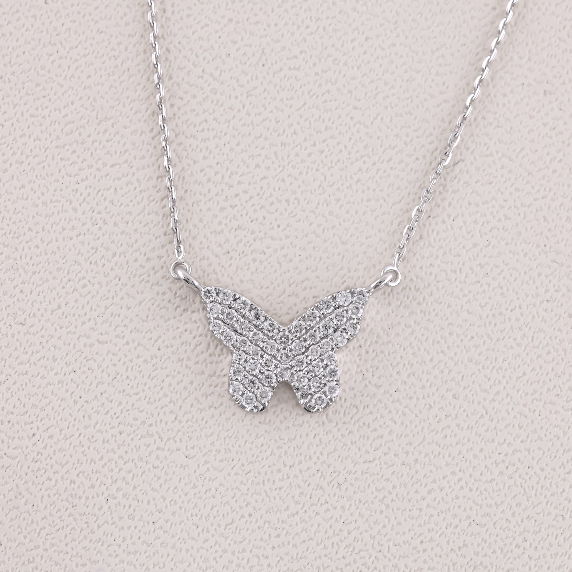 Butterfly-shaped necklace with sparkling stones on a light gray background