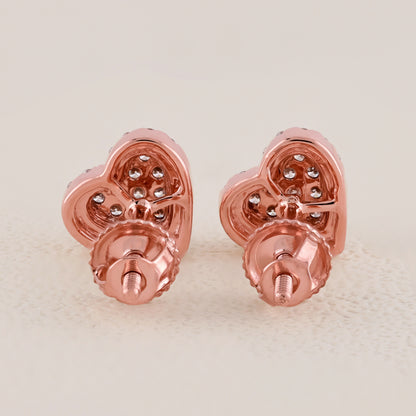 Rose gold heart-shaped earrings with embedded stones on a light beige background