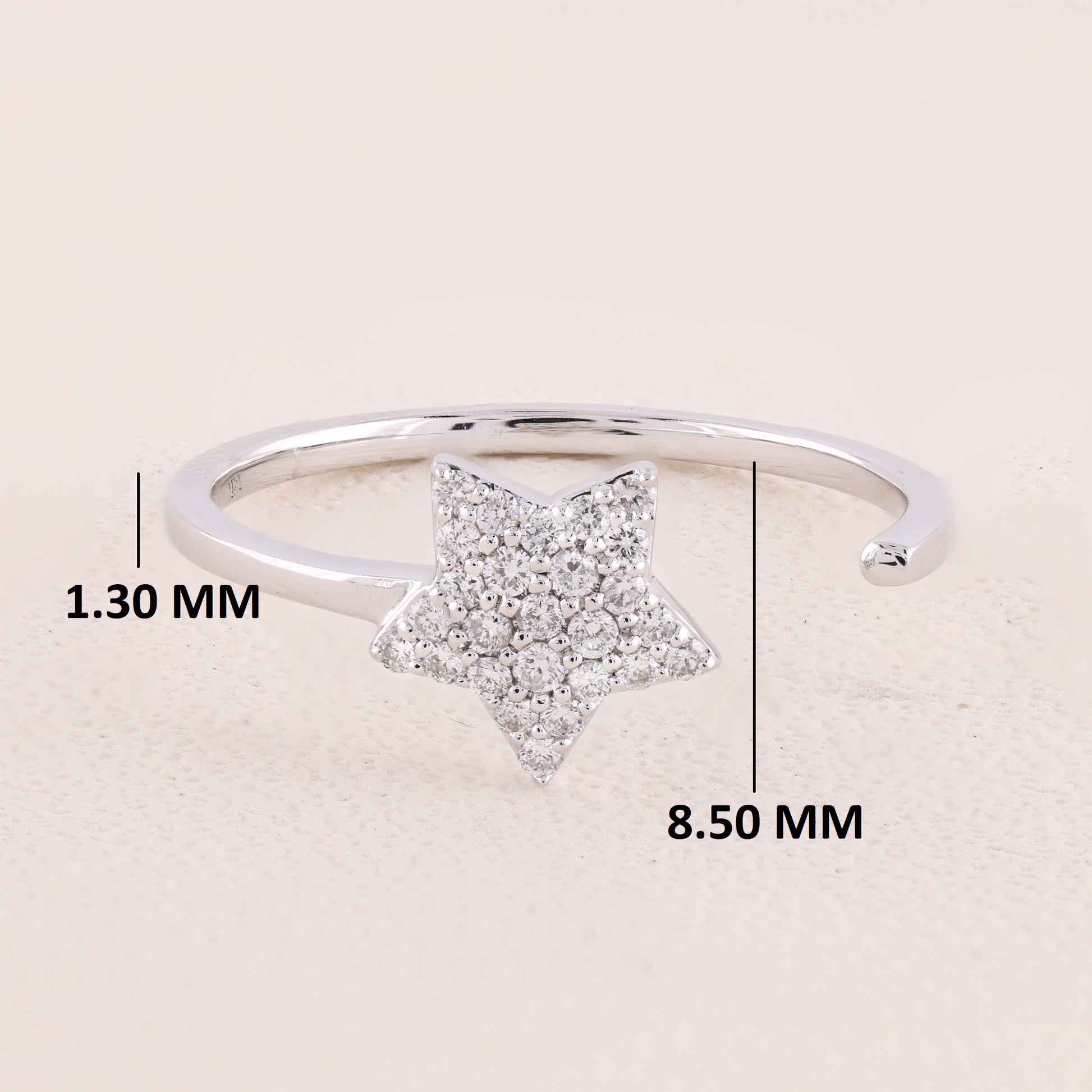 Silver ring with star design and measurements on a beige background