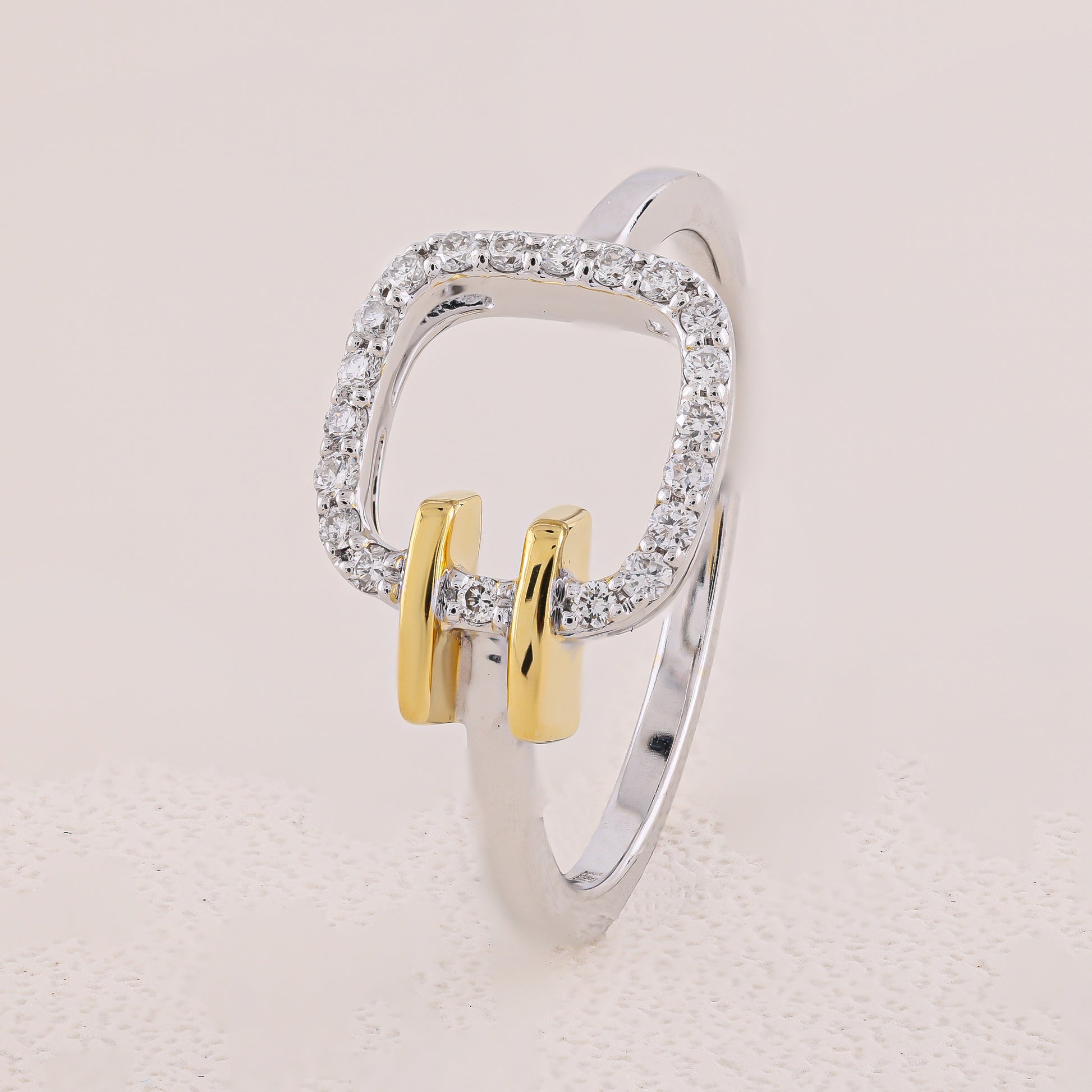 Silver and gold ring with diamond accents on a light beige background