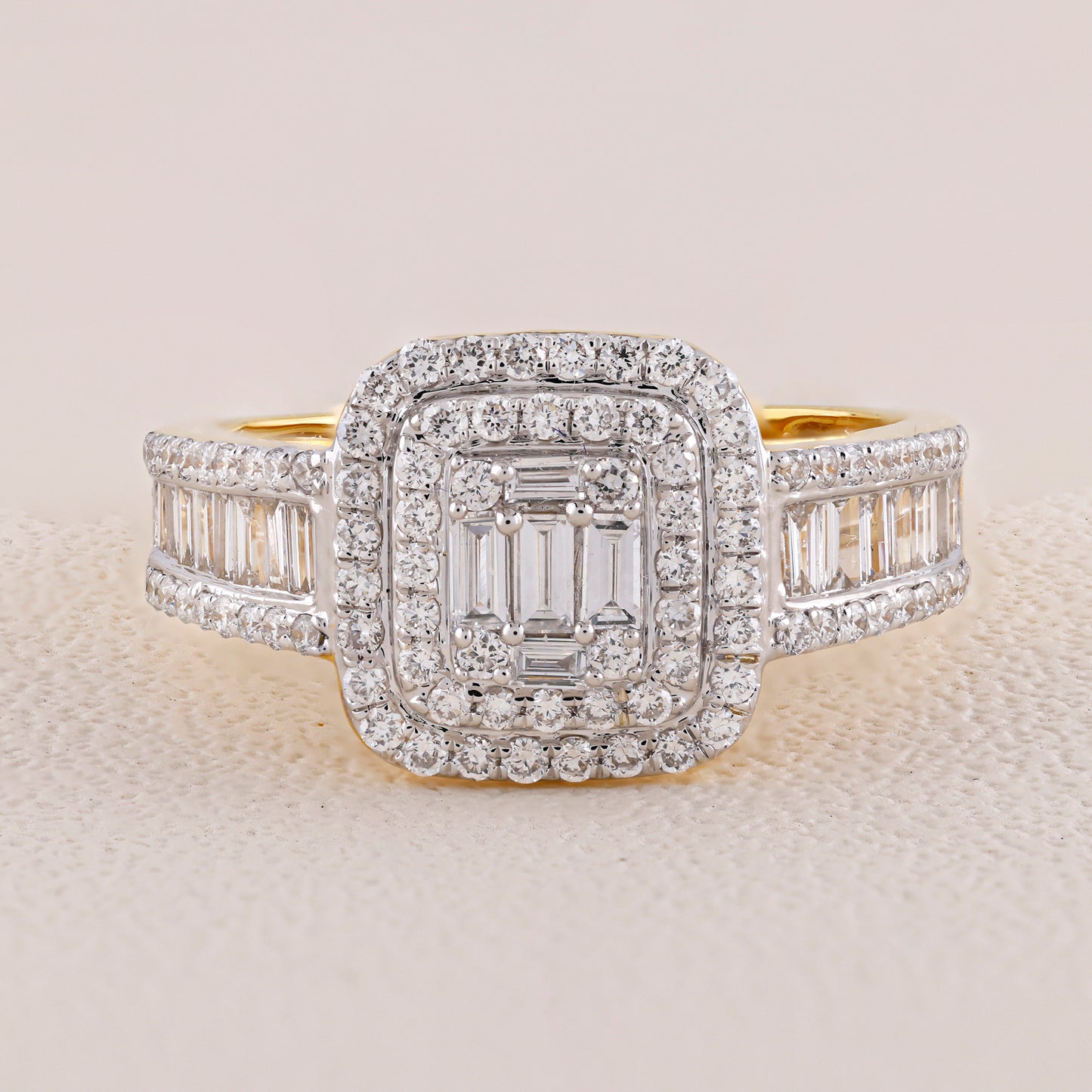 Diamond ring with a central emerald-cut stone and baguette side stones on a light background