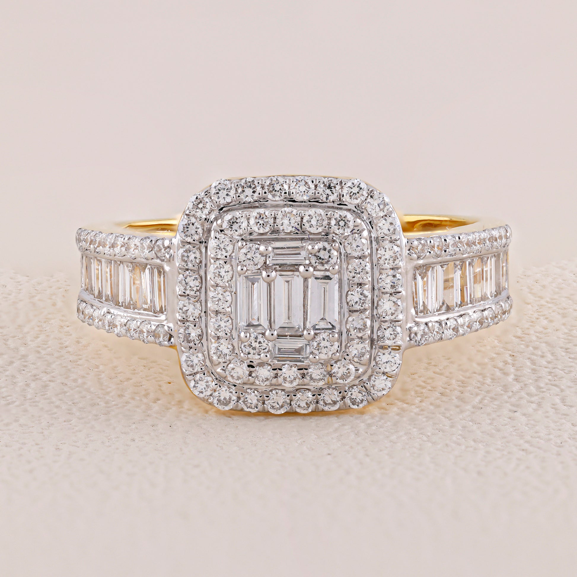 Diamond ring with a central emerald-cut stone and baguette side stones on a light background