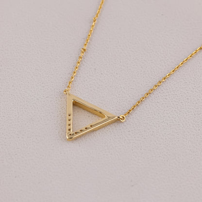 Gold triangle pendant necklace on a light gray background