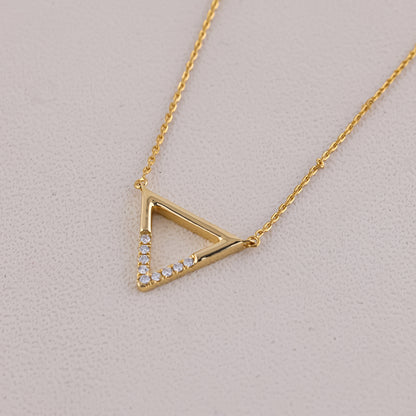 Gold triangle-shaped necklace with embedded stones on a light gray background