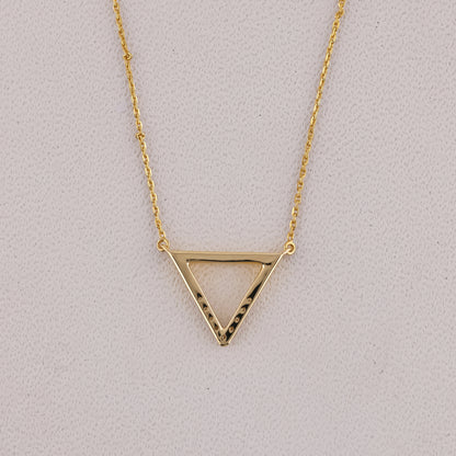 Gold triangle pendant necklace on a light gray background
