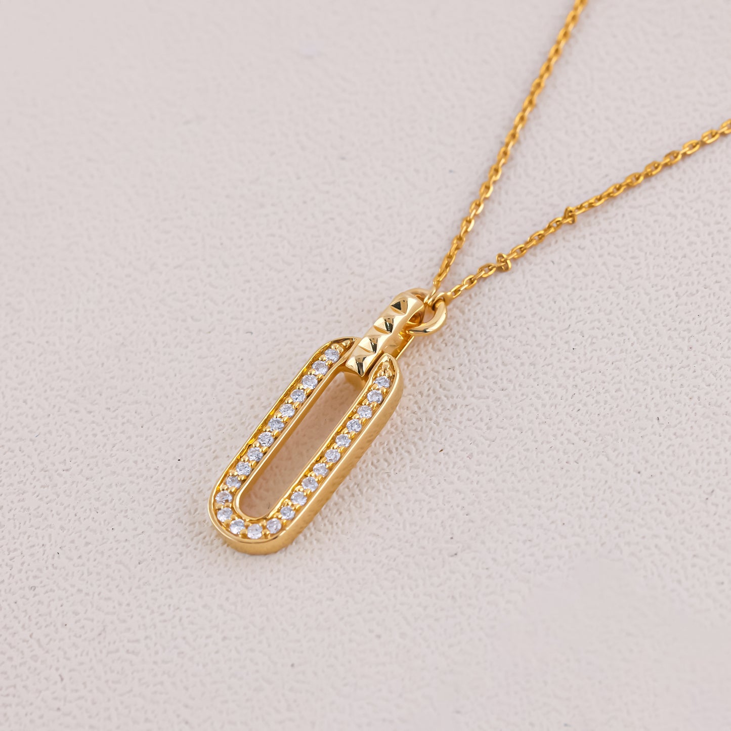 Gold necklace with a pendant on a light gray background