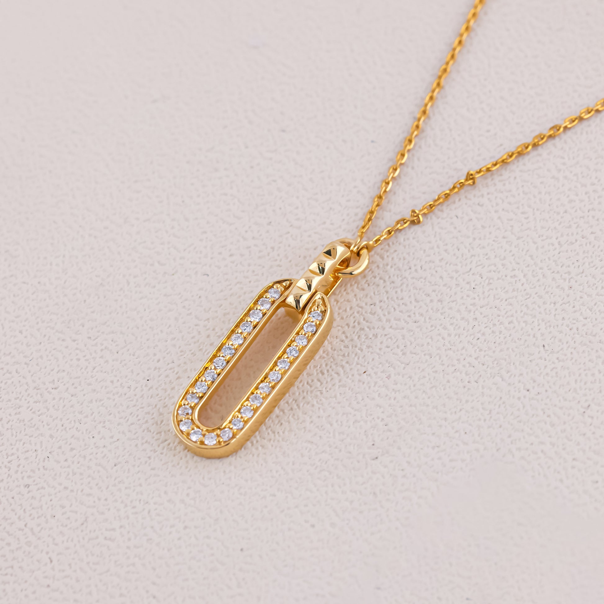 Gold necklace with a pendant on a light gray background