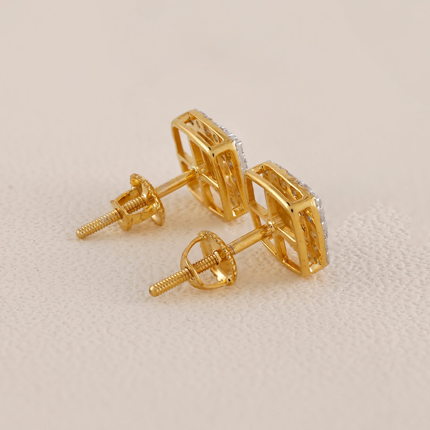 Gold earrings on a beige background