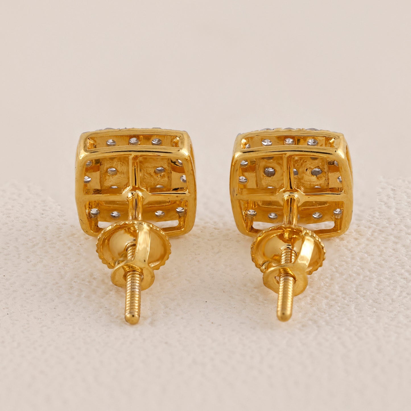 Pair of gold earrings with small diamonds on a beige background