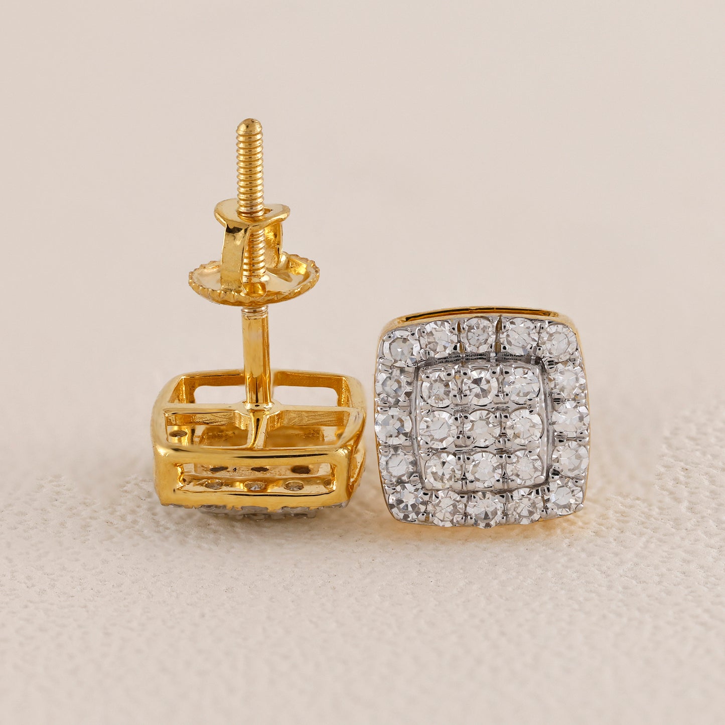 Gold earring with diamond-studded square design on a beige background