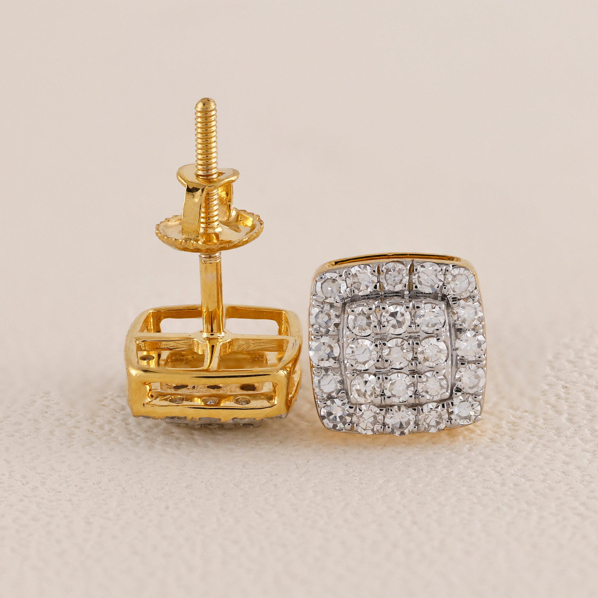 Gold earring with diamond-studded square design on a beige background