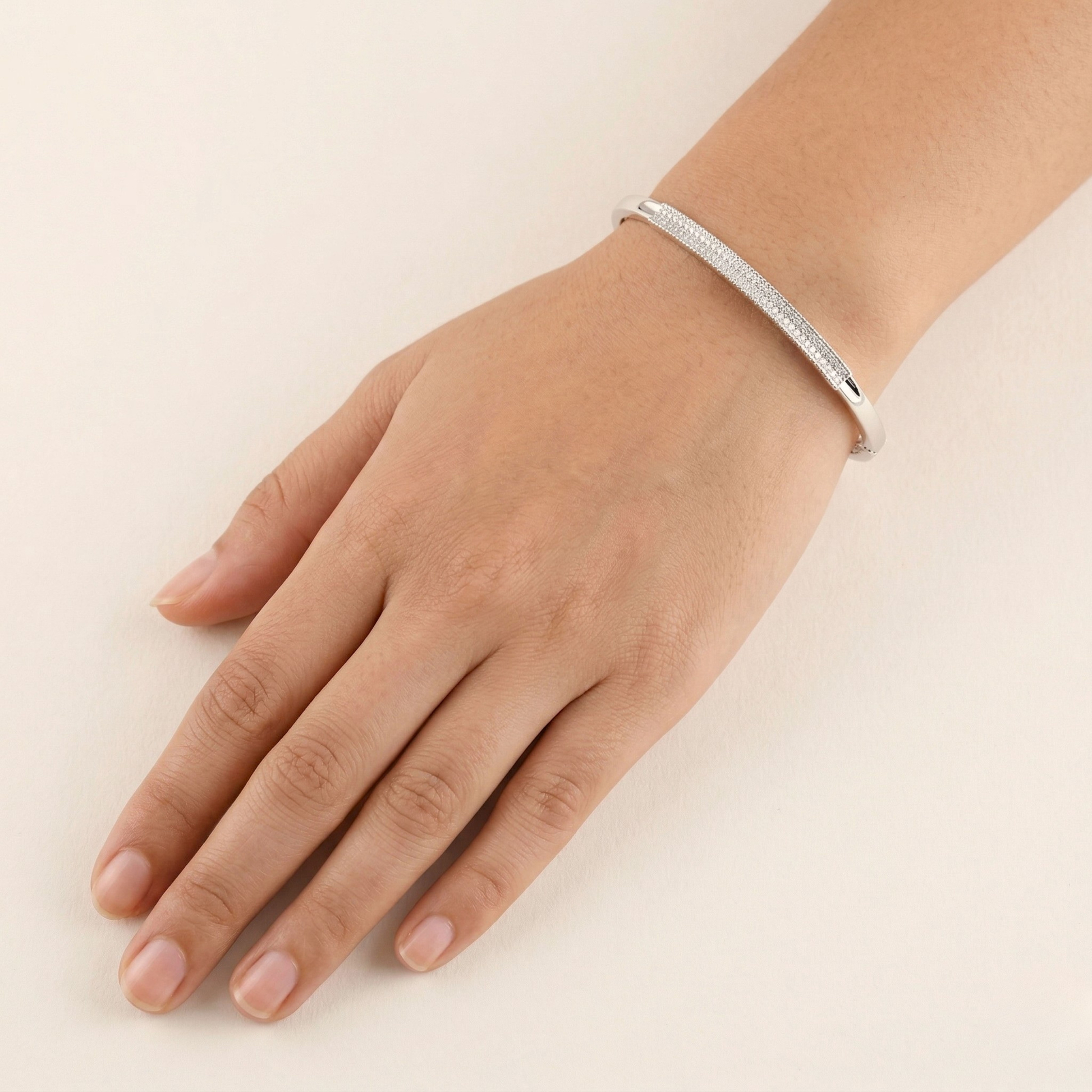 Silver bracelet on a person's wrist against a plain background