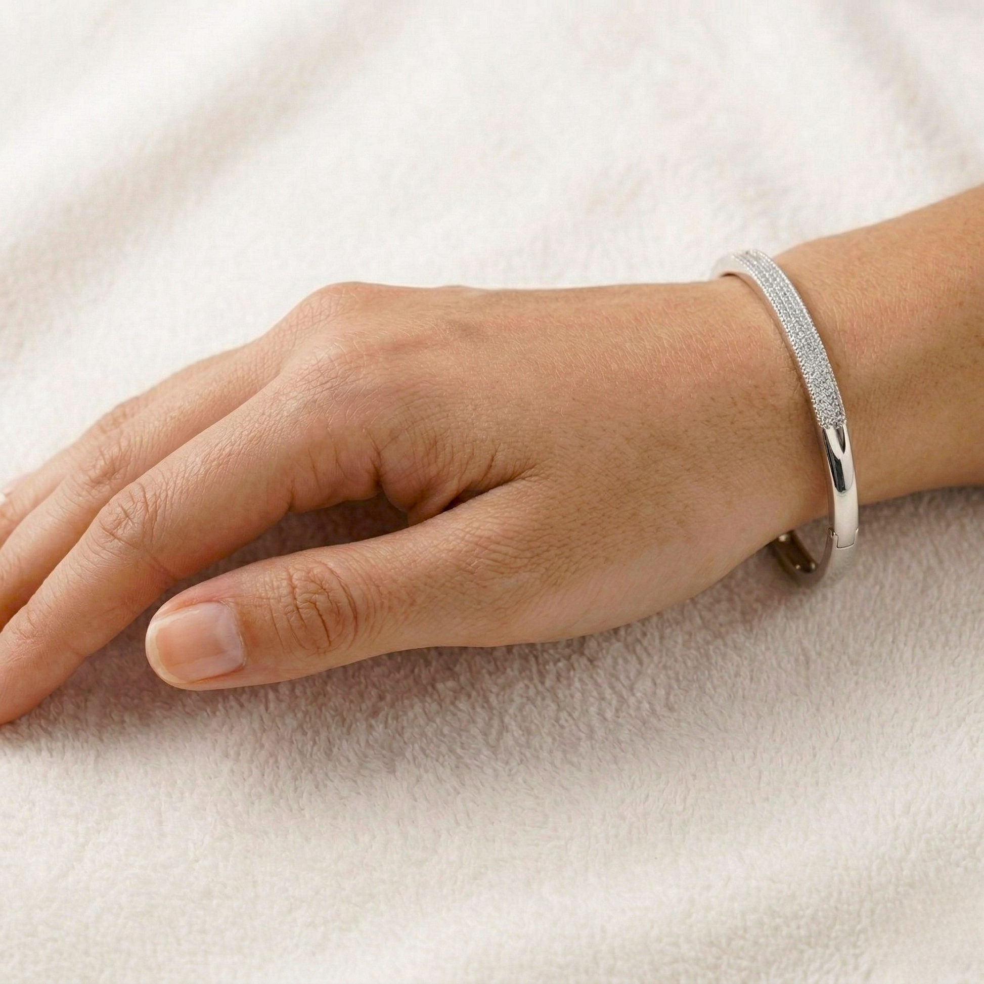 Silver bracelet on a person's wrist against a light background