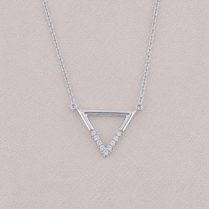Silver triangle necklace with small diamonds on a light pink background