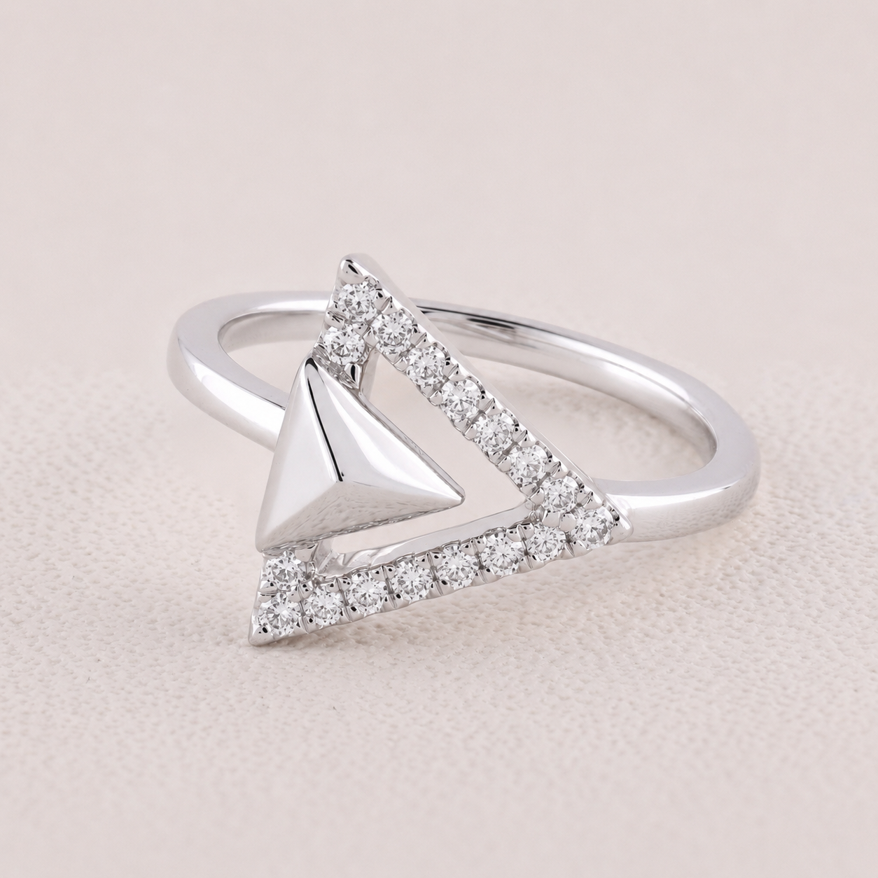 Silver ring with a triangle design on a light pink background