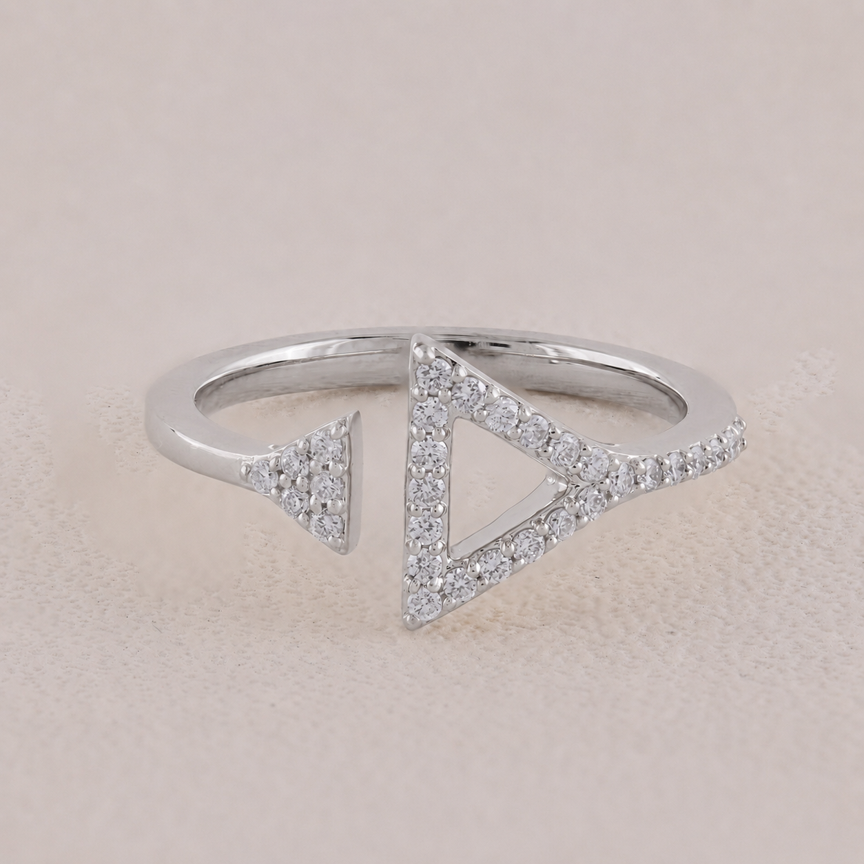 Silver ring with triangle designs on a beige background