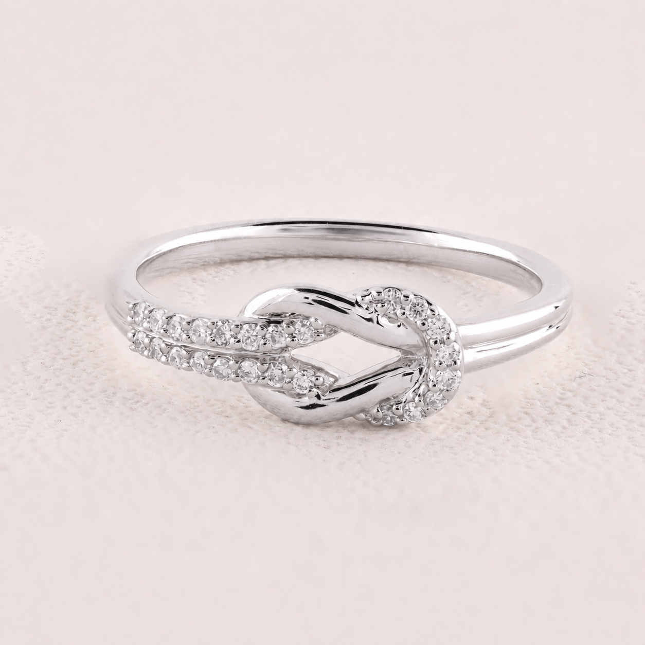 Silver ring with diamond accents on a light pink background