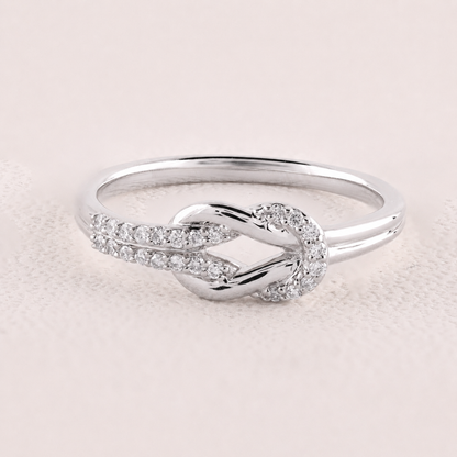 Silver ring with diamond accents on a light pink background