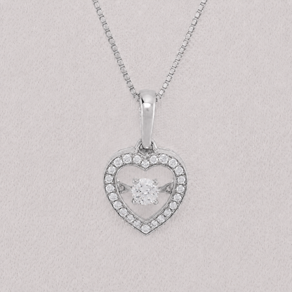 A silver heart-shaped pendant necklace with a halo border of small clear stones and a central round-cut stone, suspended from a delicate silver chain against a light gray textured background.