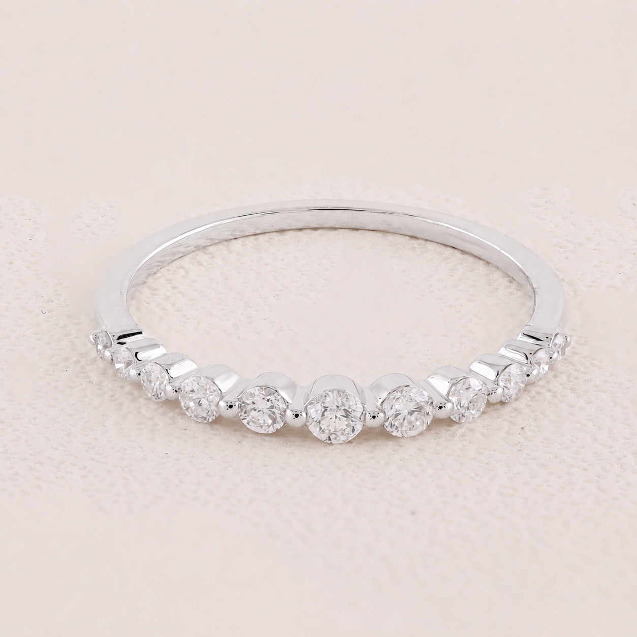 Silver ring with small diamonds on a light pink background