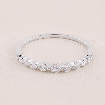 Silver ring with small diamonds on a light pink background