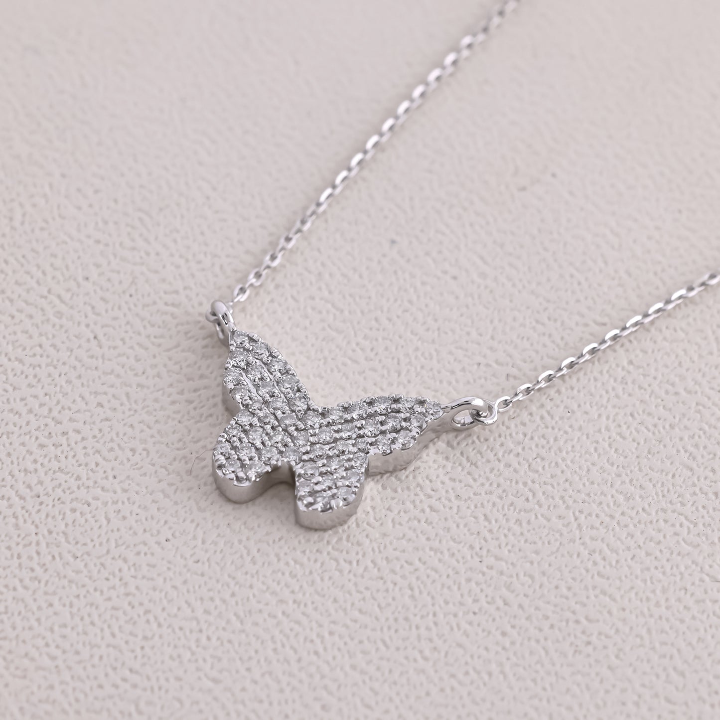 Silver butterfly necklace on a light gray background