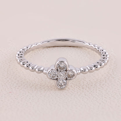 Silver ring with a clover-shaped diamond on a beige background
