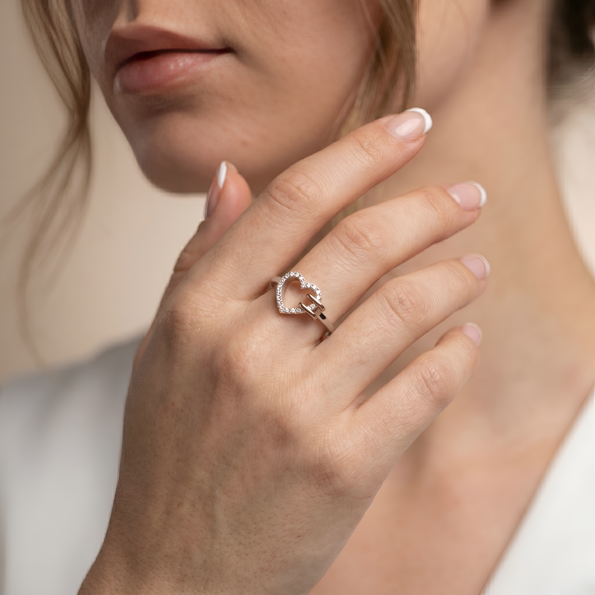 Close-up of a hand wearing a heart-shaped ring with a blurred background