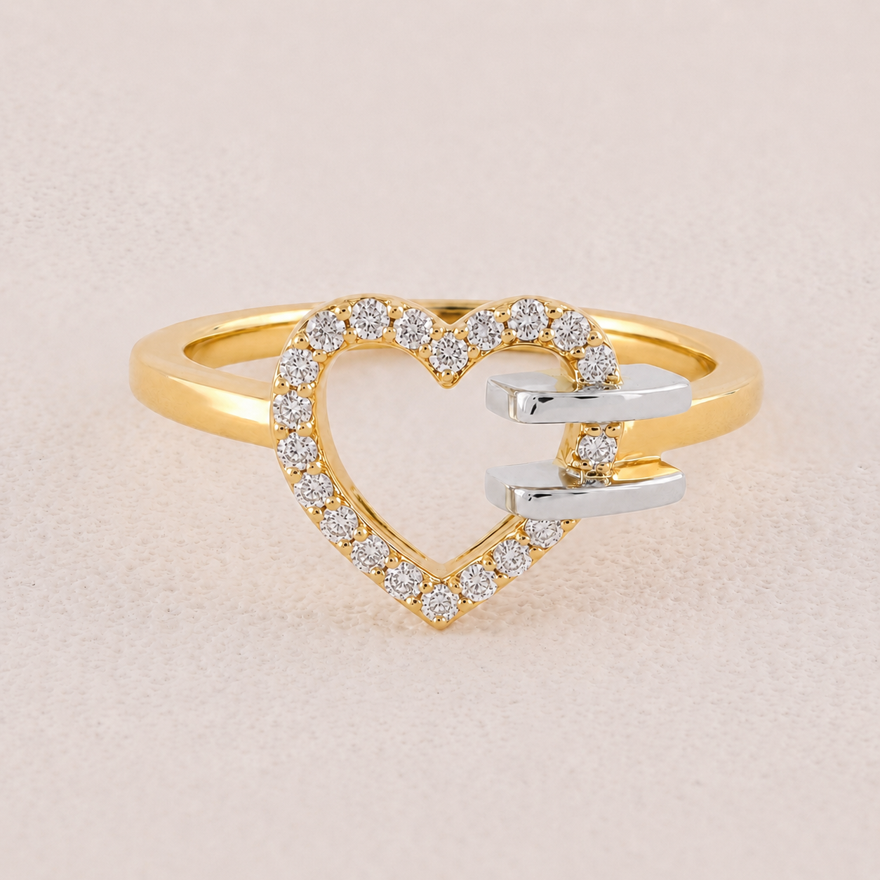 Gold and silver heart-shaped ring with diamond accents on a beige background