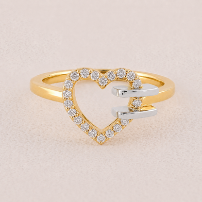 Gold and silver heart-shaped ring with diamond accents on a beige background