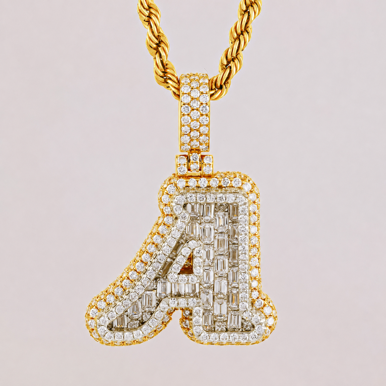 Gold necklace with a diamond-encrusted letter 'A' pendant on a light pink background