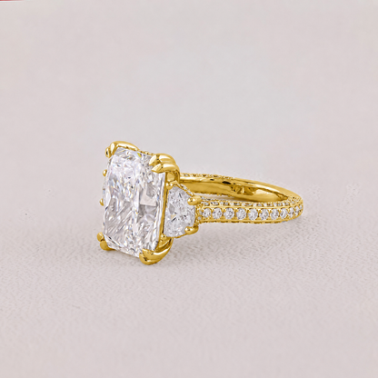 Gold ring with a large diamond and smaller diamonds on the band against a light gray background