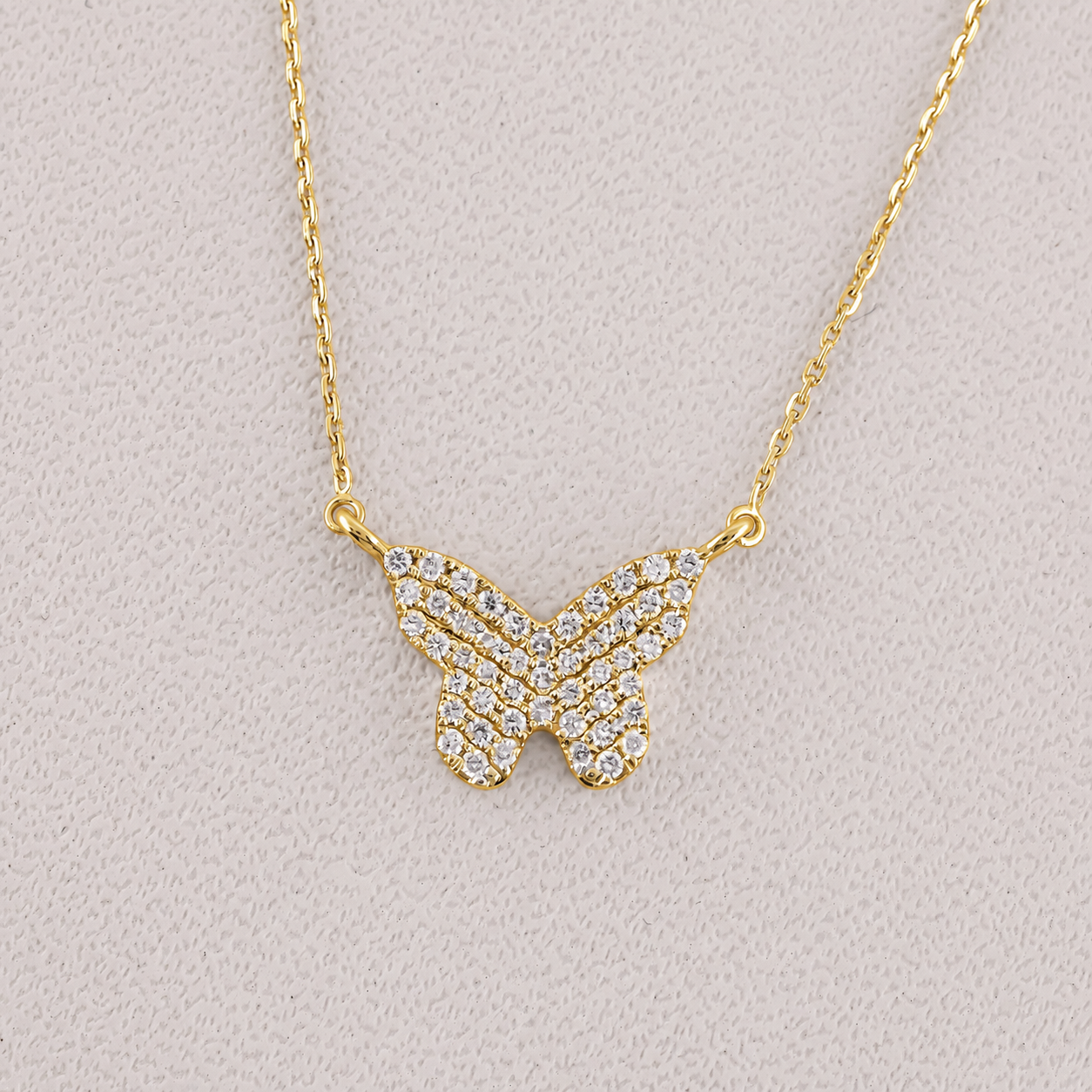 Gold butterfly necklace with diamond accents on a light gray background