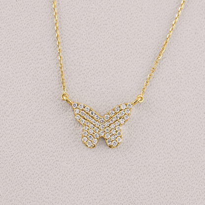 Gold butterfly necklace with diamond accents on a light gray background