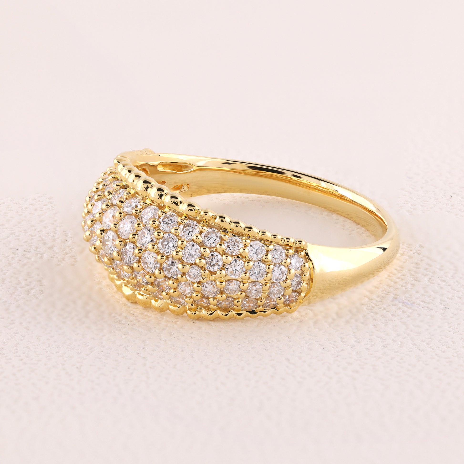 Gold ring with diamond accents on a light pink background